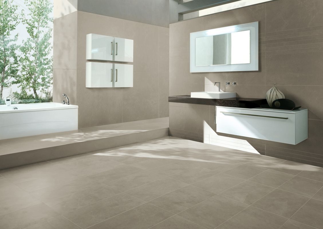 Modernes Badezimmer mit Fliesen und Naturstein – Weiße Badewanne, Waschtisch und große Fensterfront mit Blick ins Grün